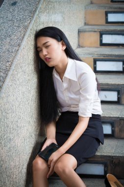 Genç iş kadını çalışma ve biraz dinlen ofis dışında siting yoruldu. Kafasını duvara yaslan.