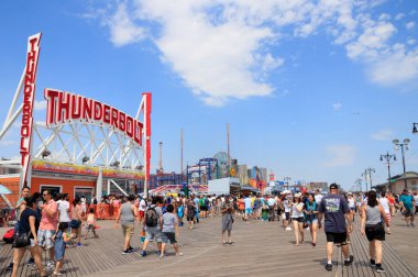 New York, ABD - 4 Temmuz 2017: İkonik kaldırım ve Coney Adası 'ndaki lunapark yazın kalabalık oluyor. Thunderbolt 'un önünde sürüş devam ediyor.