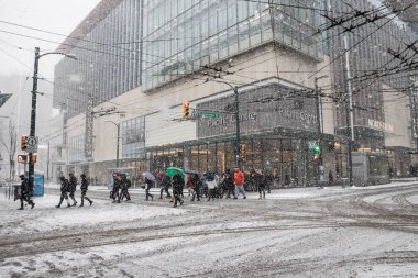 Vancouver, CANADA - 23 Şubat 2018: Kanada 'nın Vancouver kentinde kar fırtınası eşliğinde kış mevsiminde insanlar yolu yürüyerek geçerken,