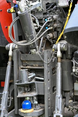 Modern bir traktörün arka hidrolik ve mekanik sisteminin detaylı görünümü, tarım makineleri eklentileri için kullanılan hortumları, eklemleri ve bağlantıları gösterir