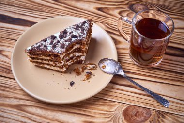 Bir tabak, fincan siyah çay, kaşık dokulu ahşap zemin üzerine kesilmiş bir parça ile çikolatalı kek