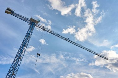 Yüksek binaların yapımında yük kaldırmak için kule vinçleri. Bulutlu gökyüzüne karşı uzun inşaat vinçleri.