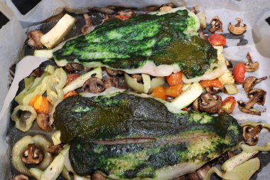 Fırında sebzeli fırın ile fırında balık fileto, üzerinde yeşil bitki sosu konsepti olan sağlıklı beslenme, ev yapımı mutfak ve diyet yemekleri.