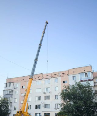 Construction crane in front of multi-story residential building on a sunny day  urban development, technical dynamics, and city infrastructure for architectural content, logistics projects