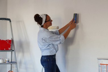 Kadın duvarları boyayarak evinin rengini değiştirmek için renk paletine bakıyor.