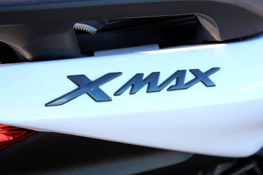 Vinnytsia, Ukraine; September 06, 2025. Close-up of Yamaha Xmax badge in glossy black finish on white surface of Yamaha scooter. Letters are stylized and reflect light with metallic sheen.