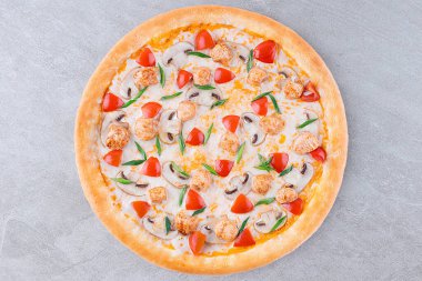 Izgara tavuk parçaları, dilimlenmiş mantarlar, kiraz domatesleri ve erimiş peynir tabanı ve altın kabuklu yeşil soğan garnitürlü pizzanın üst görüntüsü..