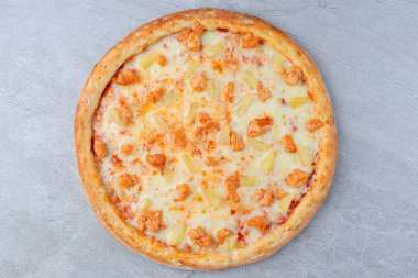 Erimiş peynir ve domates soslu ananas ve ızgara tavukla kaplı yuvarlak pizza, altın hamurda pişmiş..