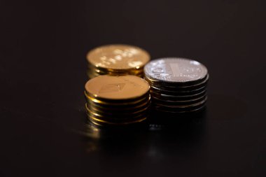 Siyah arka planda Bitcoin, Ethereum ve Litecoin 'i temsil eden metalik altın ve gümüş paralarla kripto para birimi. Kripto yatırımları, dijital zenginlik, engelleme eğilimleri ve ekonomik bozulma