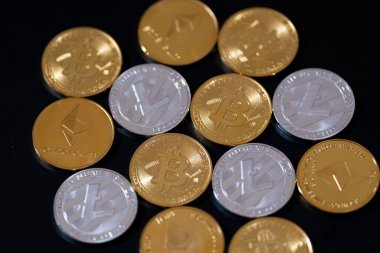 Siyah arka planda Bitcoin, Ethereum ve Litecoin 'i temsil eden metalik altın ve gümüş paralarla kripto para birimi. Kripto yatırımları, dijital zenginlik, engelleme eğilimleri ve ekonomik bozulma