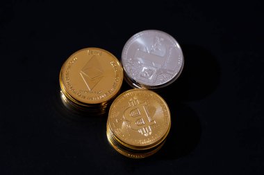 Siyah arka planda Bitcoin, Ethereum ve Litecoin 'i temsil eden metalik altın ve gümüş paralarla kripto para birimi. Kripto yatırımları, dijital zenginlik, engelleme eğilimleri ve ekonomik bozulma