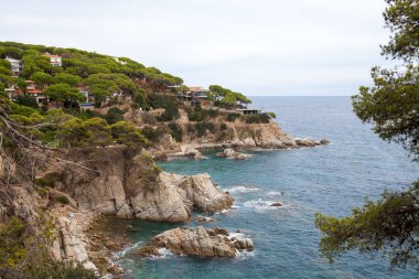 Bir Lloret de Mar / İspanya - 27 Haziran 2018: sahil Lloret de Mar, Costa Brava sahilden. İnsanlar Sahilde şezlong şemsiye altında yalan. Bir kale şehir sahilde altında istirahat.