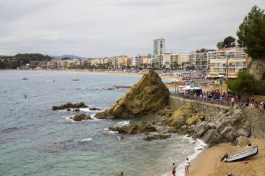 Bir Lloret de Mar / İspanya - 27 Haziran 2018: sahil Lloret de Mar, Costa Brava sahilden. İnsanlar Sahilde şezlong şemsiye altında yalan. Bir kale şehir sahilde altında istirahat.