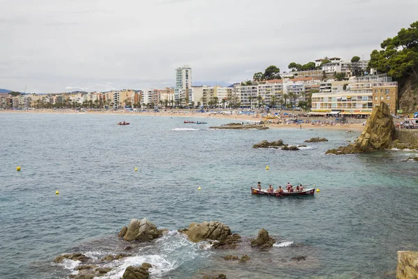 Bir Lloret de Mar / İspanya - 27 Haziran 2018: sahil Lloret de Mar, Costa Brava sahilden. İnsanlar Sahilde şezlong şemsiye altında yalan. Bir kale şehir sahilde altında istirahat.