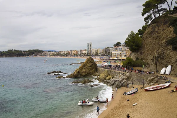 Bir Lloret de Mar / İspanya - 27 Haziran 2018: sahil Lloret de Mar, Costa Brava sahilden. İnsanlar Sahilde şezlong şemsiye altında yalan. Bir kale şehir sahilde altında istirahat.