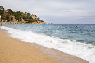 Bir Lloret de Mar / İspanya - 27 Haziran 2018: Castell d'en Plajan Costa Brava ve şehir beach Lloret de Mar, İspanya. Kum ve deniz dalgaları.