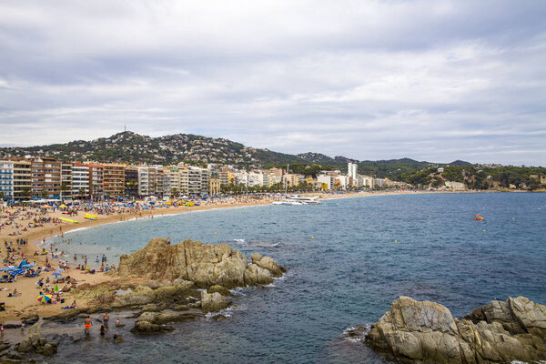 Beach in the city of Lloret de Mar on the Costa Brava. A beautiful beach in a holiday village in Spain. Buildings and hotels by the beach.