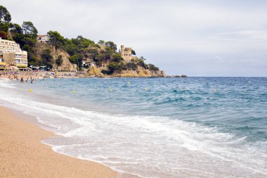 Bir Lloret de Mar / İspanya - 27 Haziran 2018: Castell d'en Plajan Costa Brava ve şehir beach Lloret de Mar, İspanya. Kum ve deniz dalgaları.