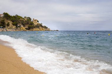 Bir Lloret de Mar / İspanya - 27 Haziran 2018: Castell d'en Plajan Costa Brava ve şehir beach Lloret de Mar, İspanya. Kum ve deniz dalgaları.
