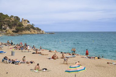 Bir Lloret de Mar / İspanya - 27 Haziran 2018: Castell d'en Plajan Costa Brava üzerinde ve şehir insanlar plaj Lloret de Mar, İspanya. Kum ve deniz dalgaları.