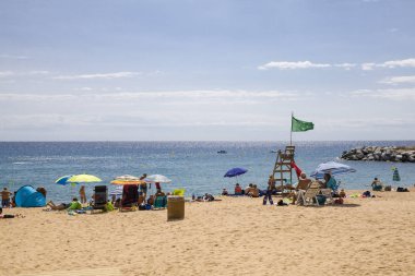 Tossa de Mar / İspanya - 27 Haziran 2018: insanlar plajda şemsiye altında. Platja de Canyelles plaj. Bir Lloret de mar ve Tossa de Mar. İspanyol sahilde Costa Brava