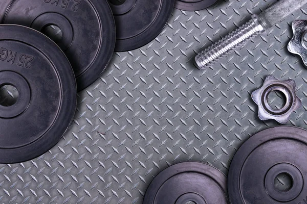 碳背景上的哑铃 哑铃和重物躺在体育馆的地板上 杠铃和健身器材 健身俱乐部中的金属负荷 — 图库照片
