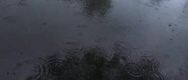 Gölet suyundaki doğal yağmur damlaları, karanlık ve sinematik geniş çekim ağır çekim