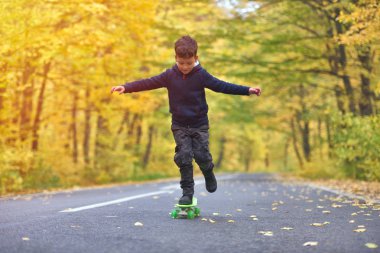 Kaykay yapıyor çocuk kaykaycı sonbahar ortamında hileler