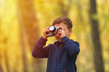 Yaratıcı çocuk, çocuk fotoğrafçı (küçük boy) renkli sonbahar orman fotoğraflarını bir fotoğraf makinesi ile