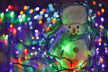 Renkli Noel ışıkları arka plan küçük oyuncak kardan adam