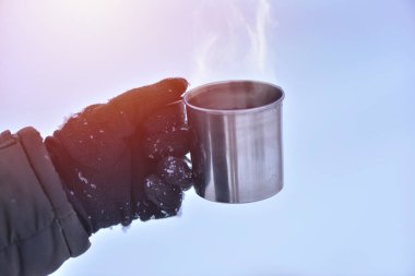 Fincan sıcak çay veya kahve ile tutarak eldiven erkek el yan görünüm. Çay molası. Kış zaman kavramı