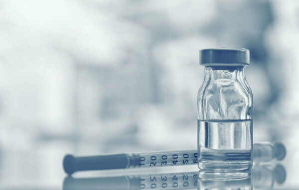 Closeup of medicine vial or flu, measles vaccine bottle with syringe and needle for immunization on vintage medical background, medicine and drug concept