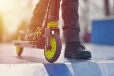 Yakın çekim tekme scooter üzerinde mavi skatepark karşı sıcak tekerlek 