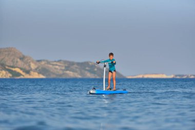 Bir Hobie üzerinde mutlu aktif çocuk kürek tahtası stand up