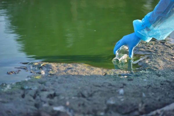 Umweltschützer aus nächster Nähe Hand eines Forschers bei der Entnahme einer Probe kontaminierten Wassers aus einem See — Stockfoto