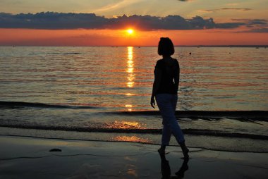 Gün batımında bir kadının silueti. Yazın son günü.