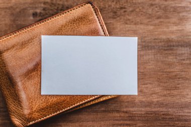 Deri çanta üzerinde beyaz iş kartı. Mockup banka kağıt ahşap doku arka plan üzerinde.