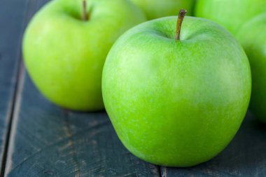 Ahşap masa arkasındaki yeşil elmayı kapat