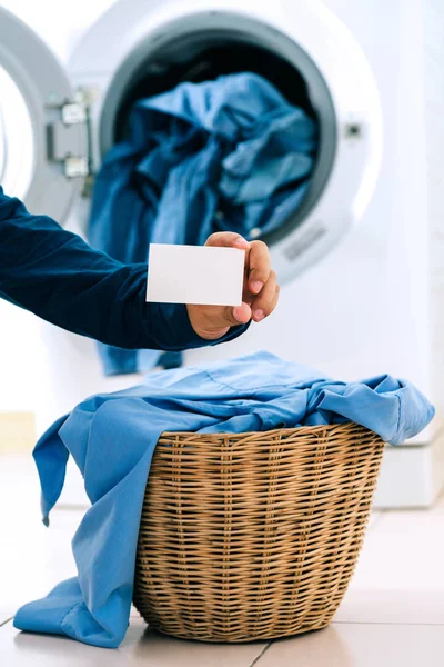 Hombre sosteniendo la tarjeta de visita vacía en la ropa en la cesta con lavabo — Foto de Stock