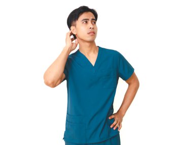 Kafasını kaşıyan önlüklü, stresli, genç Asyalı erkek hemşire beyaz arka planda izole edilmiş, kafası karışık ve üzgün bir ifade sergiliyor..