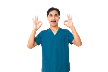 Steteskoplu heyecanlı genç Asyalı hemşire kameraya gülümserken beyaz arka planda izole edilmiş el işareti hareketi gösteriyor..