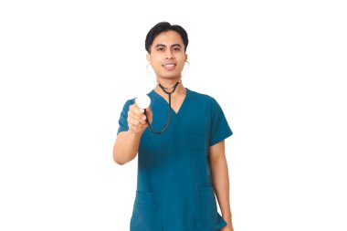 Mavi önlüklü gülümseyen genç erkek hemşire, izole edilmiş beyaz arka planda güvenle dururken steteskop tutuyor. Sağlık ve tıbbi kavramlar için mükemmel..