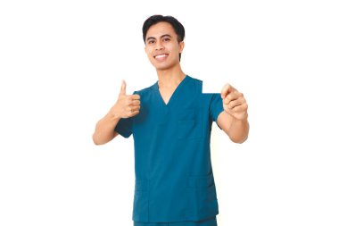 Önlüklü gülümseyen genç erkek hemşire boş bir kese ürünü tutuyor ve beyaz arka planda izole edilmiş sağlık hizmetleri ve reklamlar için baş parmak işareti yapıyor..