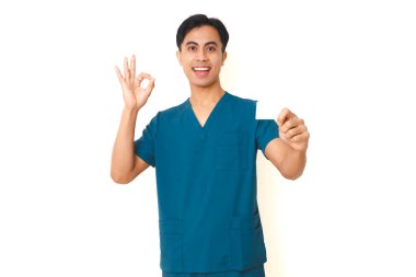 Önlüklü gülümseyen Asyalı erkek hemşire elinde boş bir kese ürünüyle beyaz arka planda izole edilmiş, sağlık ve reklamlar için mükemmel bir el hareketi gösteriyor..