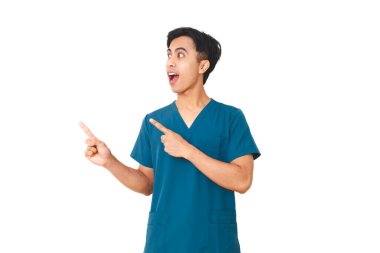 Steteskoplu heyecanlı erkek hemşire yan tarafı gösteriyor ve izole beyaz arka planda şaşırmış bir ifade sergiliyor..