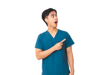 Steteskoplu heyecanlı erkek hemşire yan tarafı gösteriyor ve izole beyaz arka planda şaşırmış bir ifade sergiliyor..