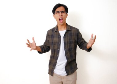 Asyalı ciddi bir adam dikilip kameraya kızgın bir ifadeyle bakıyor, beyaz bir arka planda izole edilmiş.