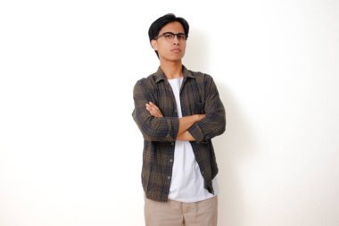 Asyalı ciddi bir adam dikilip kameraya kızgın bir ifadeyle bakıyor, beyaz bir arka planda izole edilmiş.