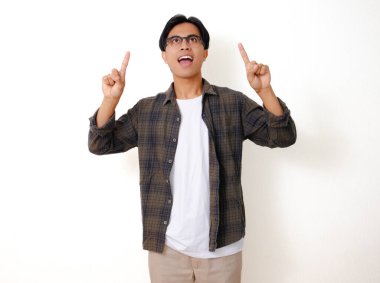 Heyecanlı genç Asyalı adam mutlu bir ifadeyle yukarı bakıyor, beyaz arka planda izole edilmiş.