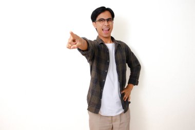Mutlu, heyecanlı genç Asyalı adam gülümseyip kamerayı işaret ediyor, izole beyaz arka planda duruyor.